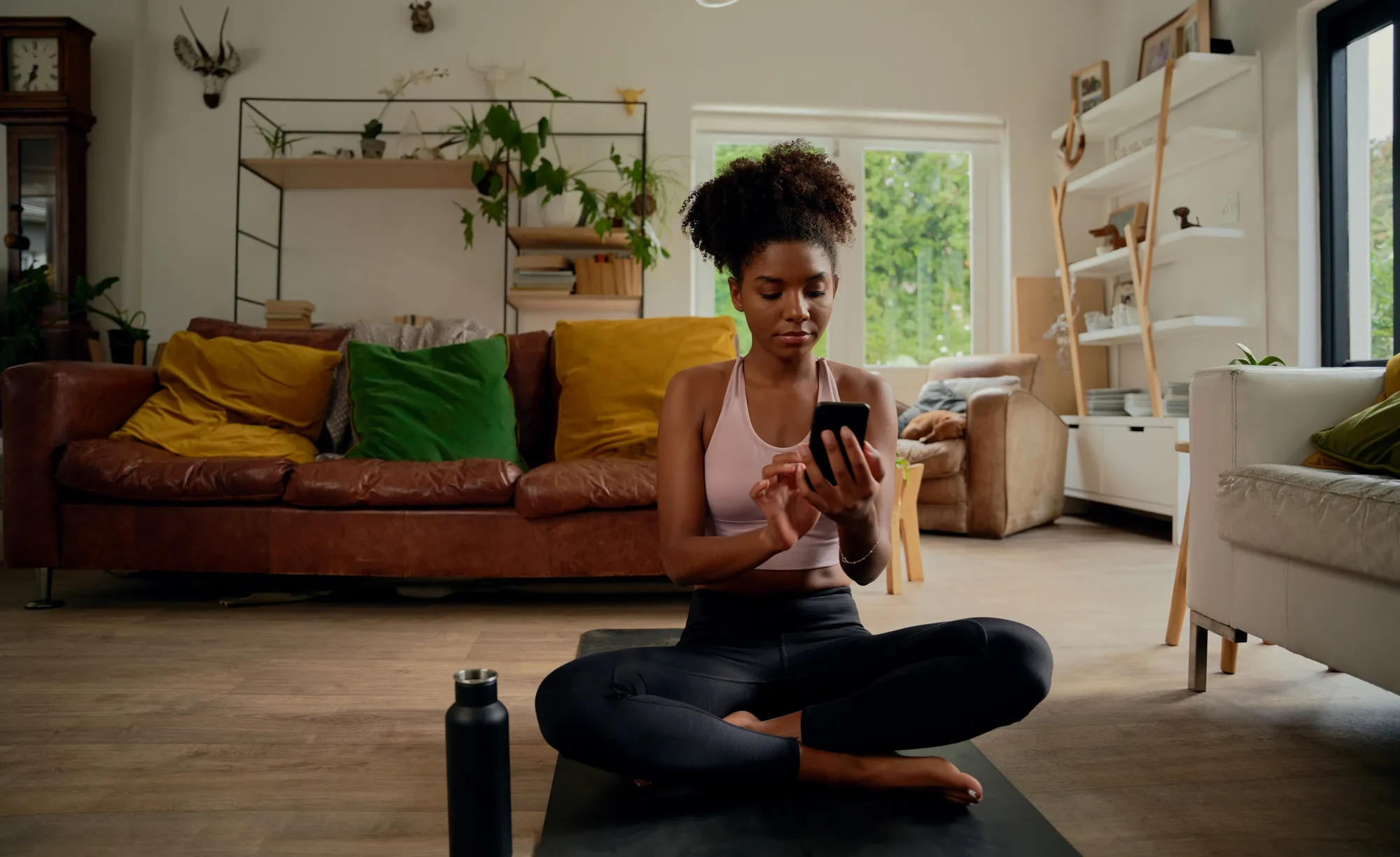 Woman doing yoga at home while checking her earned wages on a phone